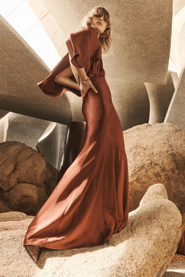 Model in a rust gown among desert rocks
