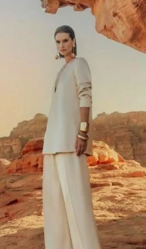 Model in an ivory suit with gold cuffs in a canyon