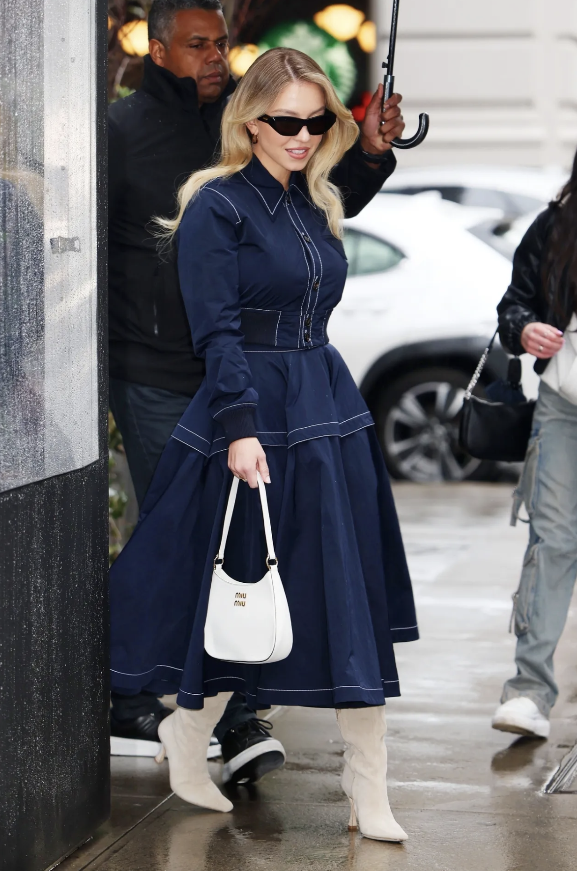 Sydney Sweeney in a denim dress, styled with a white mid mid bag and off white boots